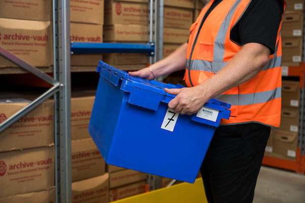 Archive vault employee transferring documents into storage